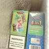 Zwei verpackte Vape-Produkte mit leuchtend bunter Verpackung, eine grüne Flasche mit der Aufschrift “4in1” neben einer blauen Schachtel mit aufgeführten Geschmacksrichtungen und einem Warnschild.