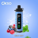 Dispositivo vape OKSO Shishai com display digital, cercado por frutas variadas e folhas de hortelã em um fundo azul, rotulado como 'Berry Mint'.