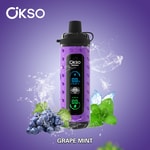 Dispositivo vape OKSO Shishai roxo com display digital, cercado por uvas, folhas de hortelã, respingos de gelo e rotulado como 'GRAPE MINT' em um fundo roxo.