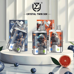 Three Crystal Twin 50K vape devices with futuristic astronaut-themed packaging displayed on a white platform, surrounded by blueberries and a halved grapefruit for flavor indication.