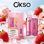 Kit OKSO per vaporizzare il ghiaccio alla fragola con bottiglia e confezione con motivo rosa, circondato da fragole e cubetti di ghiaccio.