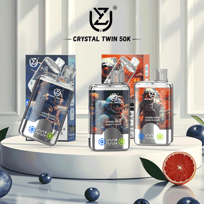 Three Crystal Twin 50K vape devices with futuristic astronaut-themed packaging displayed on a white platform, surrounded by blueberries and a halved grapefruit for flavor indication.