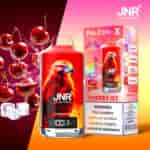 Un produit de vape rouge vif étiqueté " JNR Cherry Ice " avec une illustration d'aigle, à côté de sa boîte d'emballage affichant les détails du produit, des glaçons et des cerises en arrière-plan.