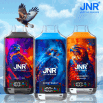 Trois bouteilles colorées d'e-liquide de marque JNR étiquetées " Peach Ice ", " Berry Burst " et " Strawberry Banana ", chacune présentant un motif de faucon vibrant sur des fonds colorés.