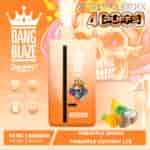Promotional image for Bang Blaze Joycome disposable vape device featuring pineapple mango and pineapple coconut ice flavors, with a skull wearing a crown, bright orange colors, and ingredients graphics of pineapple, mango, and coconut.