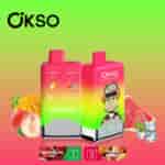 Two OKSO brand double flavor vape devices with a red and green gradient design, one featuring a cartoon monkey with headphones, surrounded by images of peach, mango, watermelon, and ice to represent the peach mango and watermelon ice flavors.