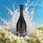 Una botella de champán oscuro con una etiqueta decorativa rosa, salpicando agua entre uvas blancas, contra un cielo azul brillante.