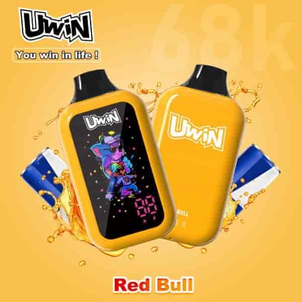 Two bright yellow Uwin handheld gaming devices with black screens and splashy cartoon graphics, one showing playful characters and the other a logo, set against a orange backdrop with Red Bull cans and liquid splashes.