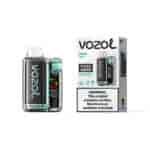 Appareil de vape Vozol Miami Mint Vista 20000 avec finition en fibre de carbone et accents turquoise à côté de son emballage en boîte blanche montrant les instructions et l'étiquette d'avertissement.