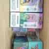 Box of colorful vape or e-liquid packaging boxes with “4 in 1” and cartoon characters; stack in a cardboard box with warning labels on front.