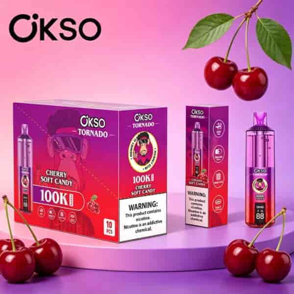 Sfondo rosa-viola brillante con diverse scatole viola OKSO Tornado e ciliegie mature appese agli steli, ciliegie sparse sulla superficie.