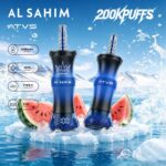Two vape devices labeled "AL SAHIM" and "ATVS" with a blue and black design, surrounded by ice and watermelon slices, against a scenic water backdrop